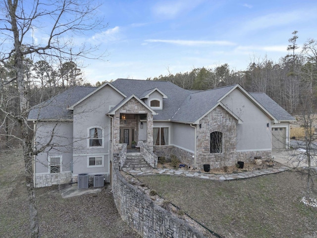 view of front of property featuring a garage, cooling unit, stone siding, and roof with shingles