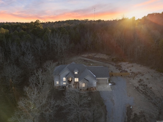 aerial view at dusk featuring a forest view