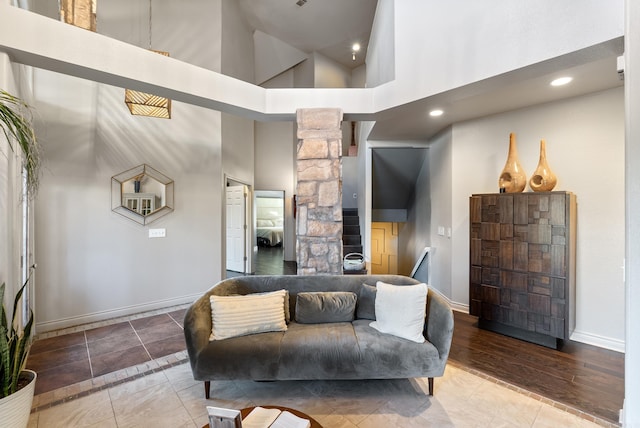 living room with recessed lighting, a high ceiling, tile patterned flooring, baseboards, and ornate columns