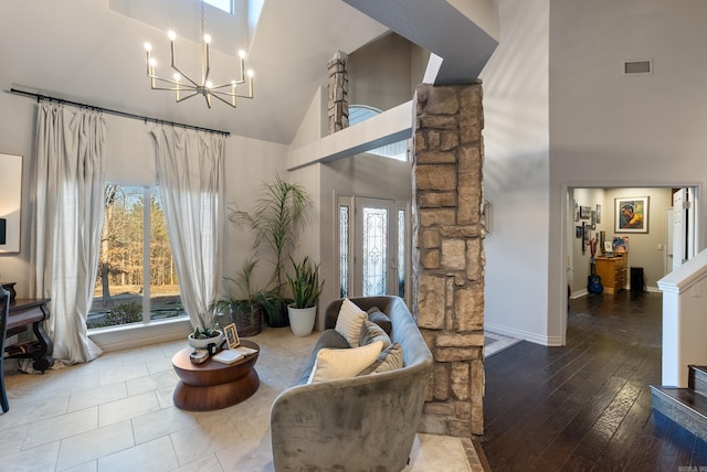 living area featuring visible vents, plenty of natural light, high vaulted ceiling, and an inviting chandelier