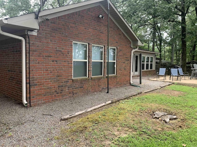 exterior space with brick siding and a patio area