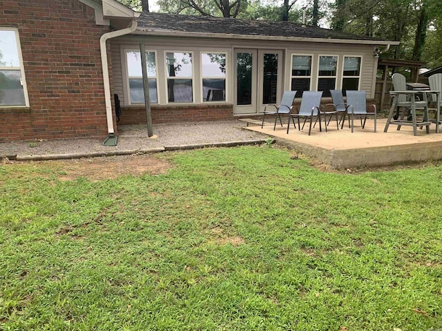 back of property with a yard, a patio, and brick siding