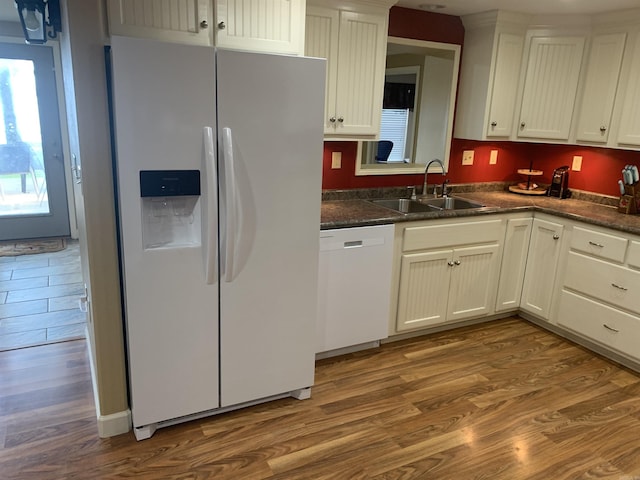 kitchen with white appliances, dark wood-style floors, a sink, white cabinetry, and dark countertops