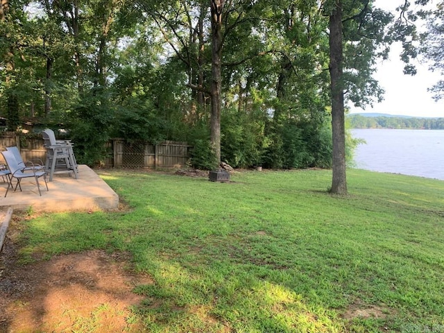 view of yard with a patio, fence, and a water view