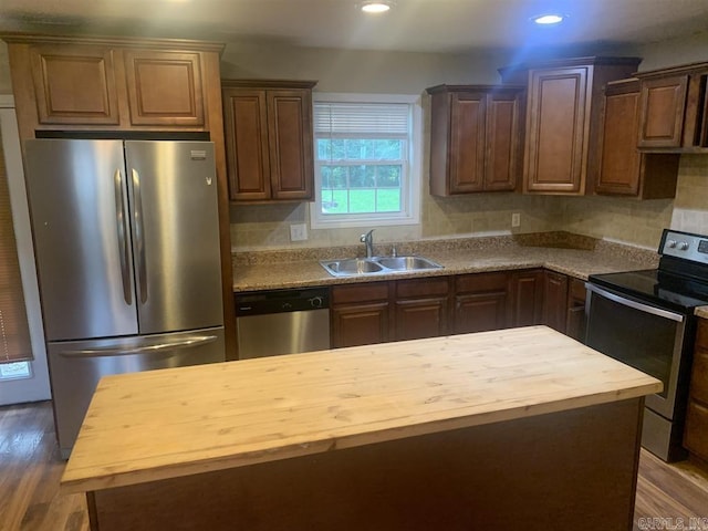 kitchen with butcher block countertops, appliances with stainless steel finishes, wood finished floors, and a sink