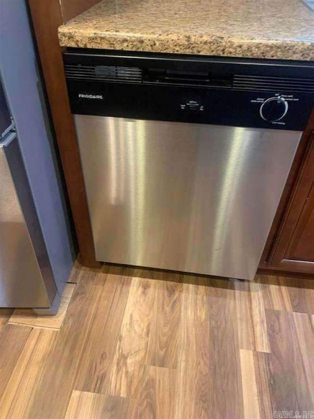 interior details with stainless steel dishwasher, light countertops, and light wood finished floors