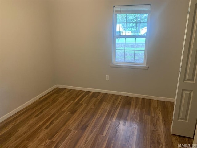 unfurnished room with dark wood finished floors and baseboards