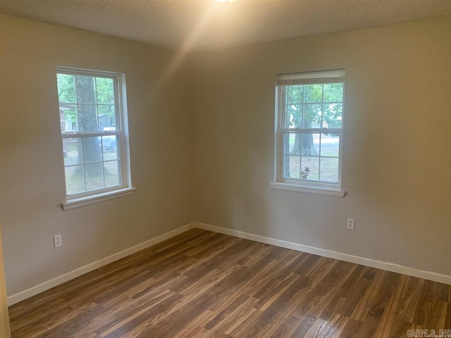 unfurnished room with baseboards, dark wood-type flooring, and a textured ceiling