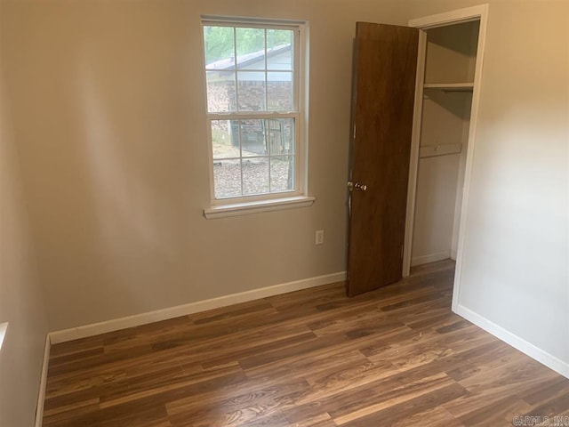 unfurnished bedroom featuring a closet, baseboards, and wood finished floors