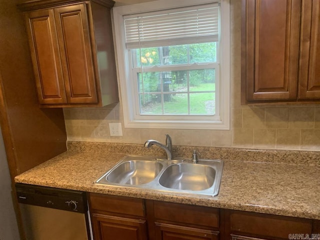 kitchen with brown cabinetry, dishwasher, light countertops, and a sink