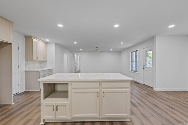 kitchen with light wood finished floors, backsplash, a center island, baseboards, and recessed lighting