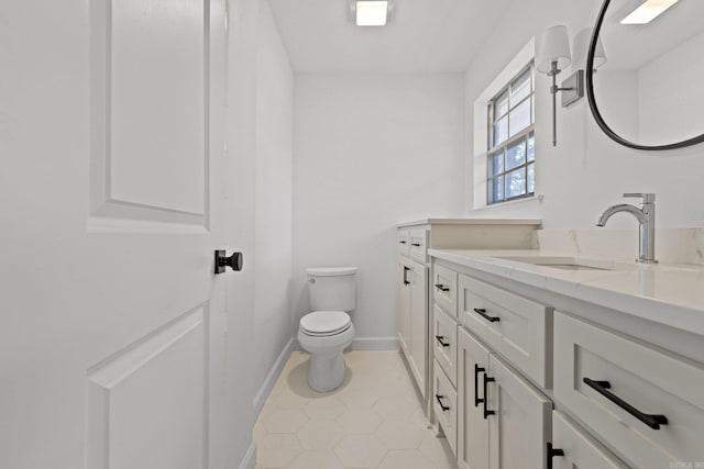 bathroom with baseboards, toilet, vanity, and tile patterned flooring