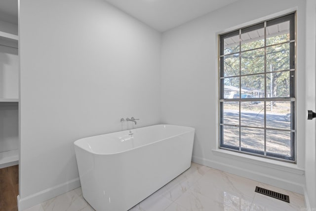 full bath featuring a wealth of natural light, visible vents, marble finish floor, and baseboards