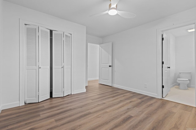 unfurnished bedroom with baseboards, ensuite bath, ceiling fan, light wood-style floors, and a closet