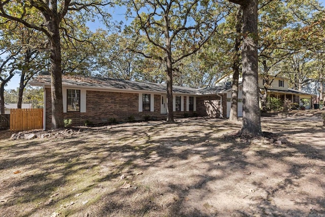 exterior space featuring driveway, brick siding, an attached garage, and fence