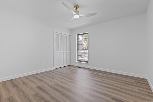 empty room with ceiling fan, baseboards, and wood finished floors