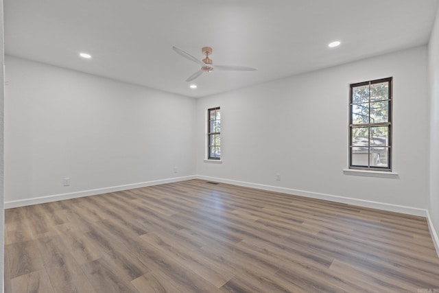 empty room with visible vents, baseboards, a healthy amount of sunlight, and wood finished floors