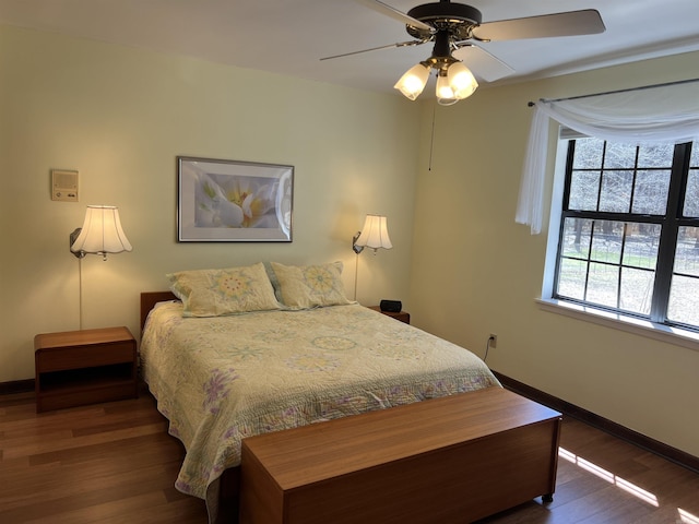 bedroom with a ceiling fan, wood finished floors, and baseboards