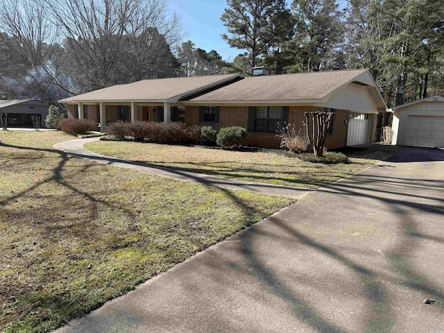 single story home featuring brick siding, an outdoor structure, and a front lawn