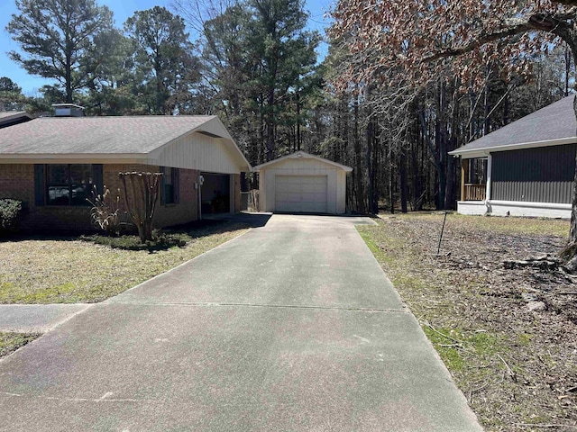 view of property exterior with brick siding, a detached garage, a sunroom, an outbuilding, and driveway