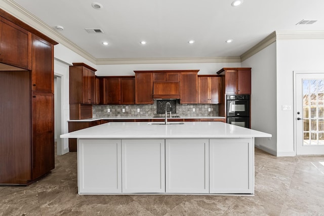 kitchen featuring visible vents, a center island with sink, dobule oven black, and light countertops