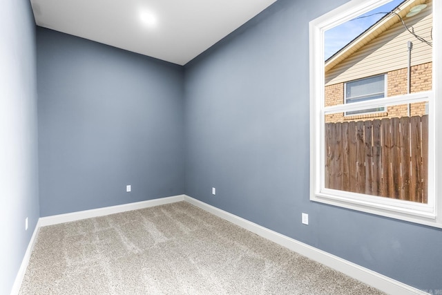 carpeted empty room featuring baseboards