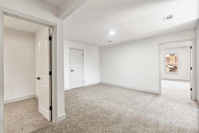 carpeted spare room featuring visible vents and baseboards