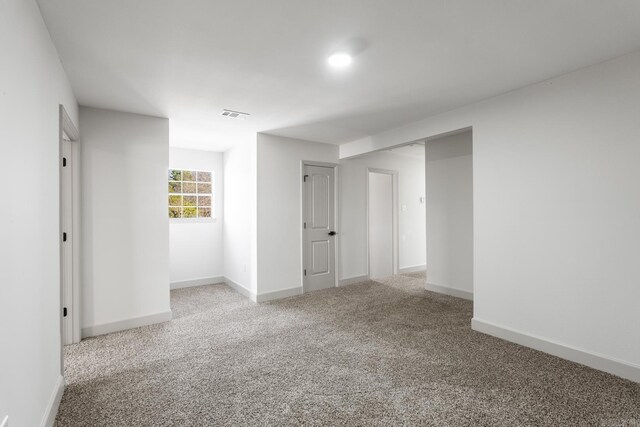 carpeted spare room featuring visible vents and baseboards