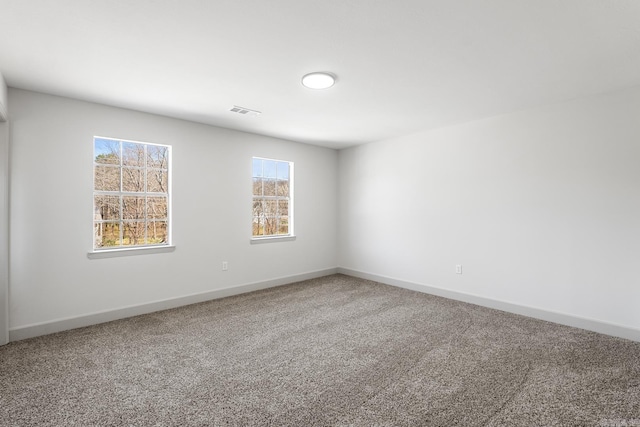 unfurnished room with visible vents, baseboards, and carpet floors