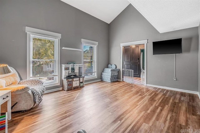 living area with high vaulted ceiling, baseboards, and wood finished floors