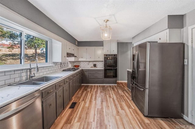 kitchen featuring a sink, tasteful backsplash, light wood finished floors, and stainless steel appliances