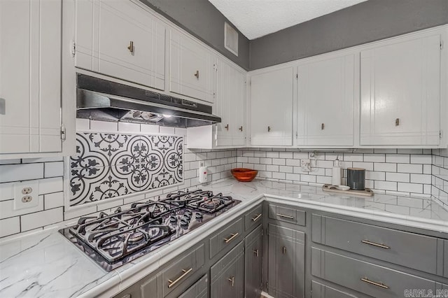 kitchen featuring under cabinet range hood, white cabinetry, black gas cooktop, and tasteful backsplash