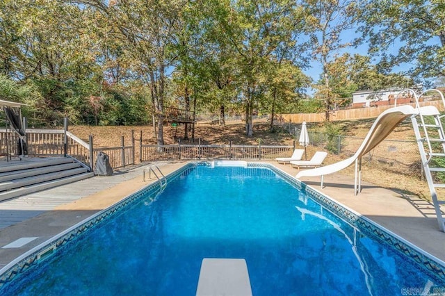 view of pool with fence, a water slide, a diving board, a fenced in pool, and a patio area