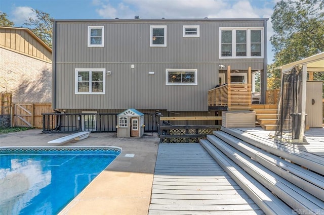 back of property with a fenced in pool, a patio area, a wooden deck, and fence