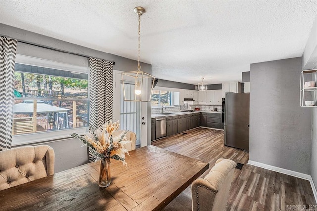 dining area with baseboards, a textured ceiling, wood finished floors, and a textured wall