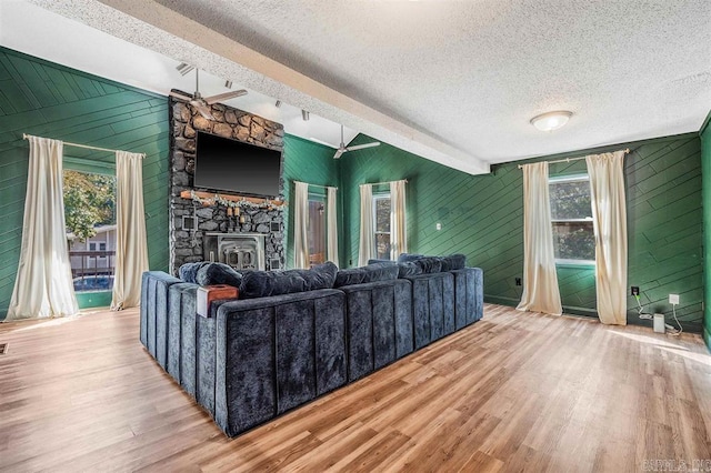 living room featuring beamed ceiling, plenty of natural light, and wood finished floors