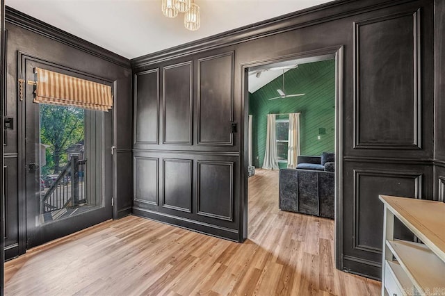 interior space featuring light wood-style flooring, vaulted ceiling, and a decorative wall