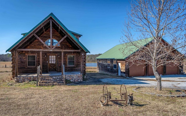 log home featuring a garage, covered porch, log exterior, and an outdoor structure