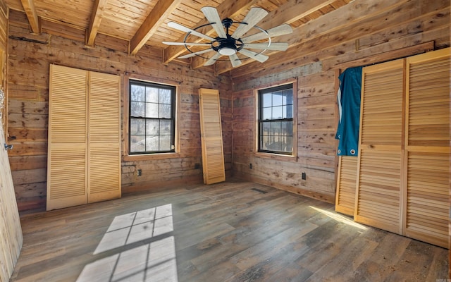 unfurnished bedroom featuring beam ceiling, wooden walls, wood finished floors, and wooden ceiling