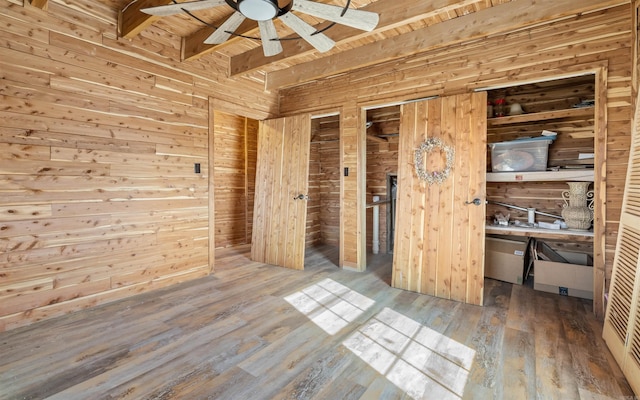 unfurnished bedroom featuring wooden walls, beamed ceiling, wooden ceiling, and hardwood / wood-style floors