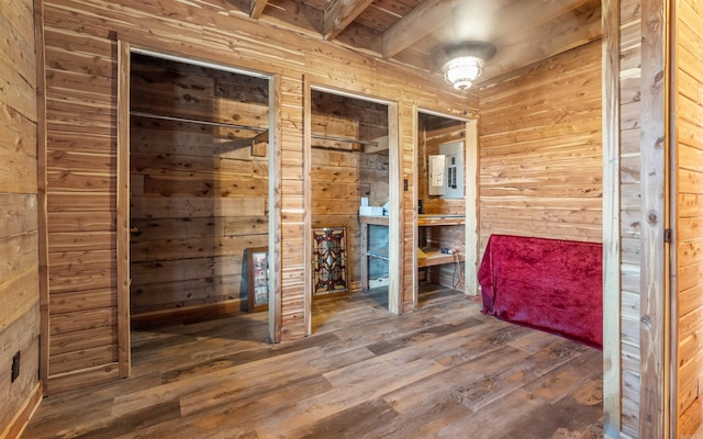 unfurnished bedroom featuring multiple closets, wooden walls, and wood finished floors