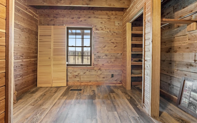 unfurnished room with wooden walls, visible vents, and wood finished floors