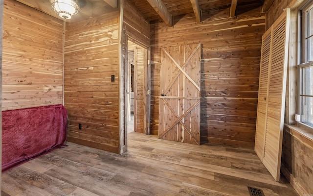 bathroom with wooden walls, visible vents, and wood finished floors