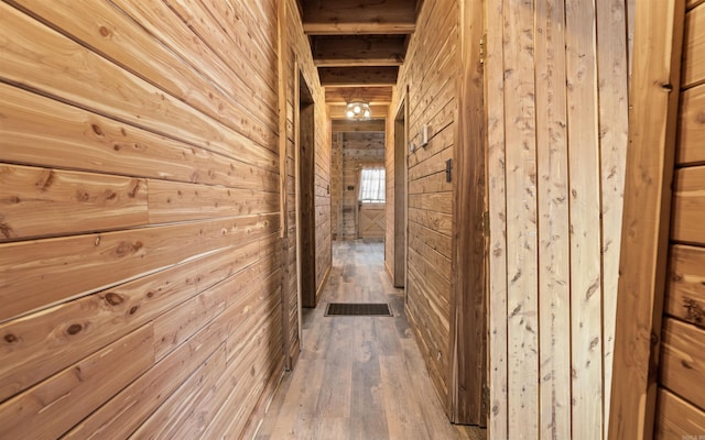 corridor featuring wooden walls, wood finished floors, and visible vents