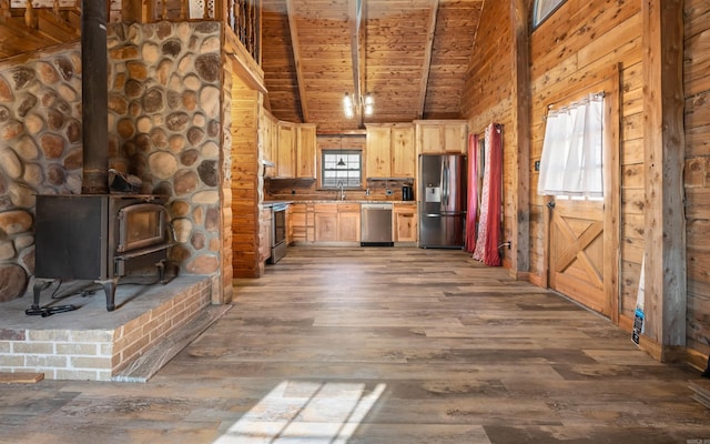 kitchen featuring a wood stove, wood finished floors, wood walls, and stainless steel appliances