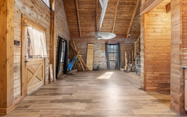 interior space featuring wooden walls, stairs, beam ceiling, wooden ceiling, and wood finished floors