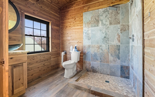 bathroom featuring vaulted ceiling, toilet, wood finished floors, and tiled shower