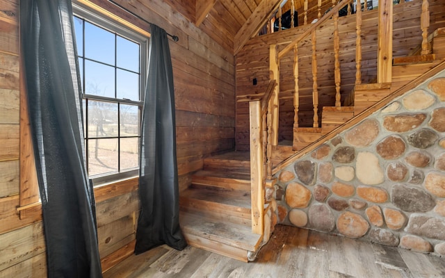 stairway with wood finished floors, wooden walls, wooden ceiling, and vaulted ceiling