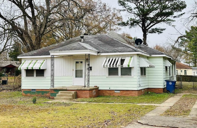 bungalow-style home featuring crawl space, roof with shingles, a front lawn, and fence