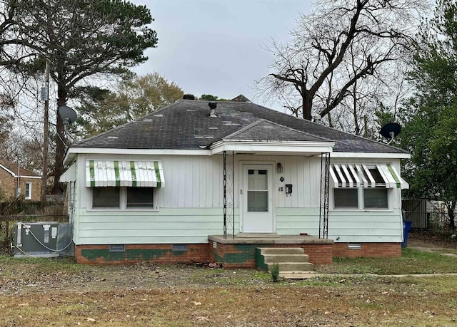 bungalow featuring crawl space, central air condition unit, a shingled roof, and fence